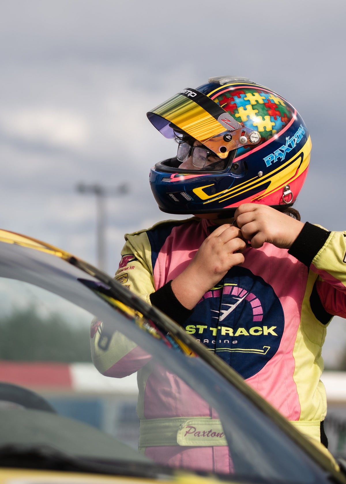 Fast Track Racing driver Paxton fastening his helmet beside the race car